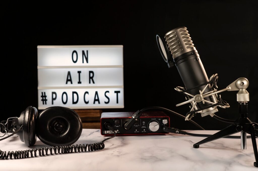 Podcast studio set with microphone, headphones, consoles and “on air” sign turned on.